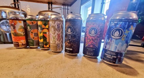 A row of colorful craft beer cans on a countertop, showcasing various designs and labels.