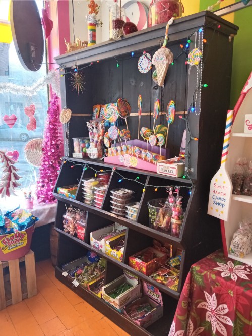A colorful candy display featuring lollipops, jars of sweets, and festive decorations in a cheerful shop setting.