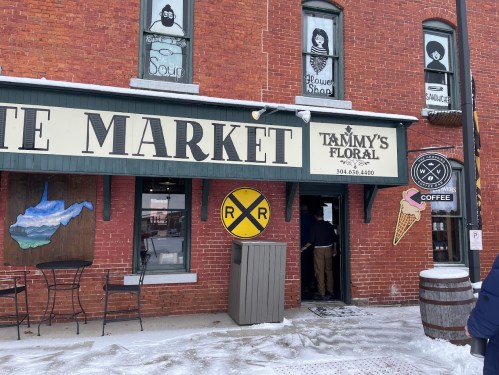 A storefront with a sign for "Tammy's Floral" and a coffee shop, featuring a railroad sign and winter decorations.