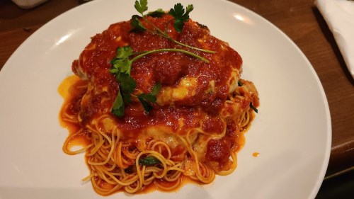 A plate of spaghetti topped with marinara sauce and garnished with parsley.