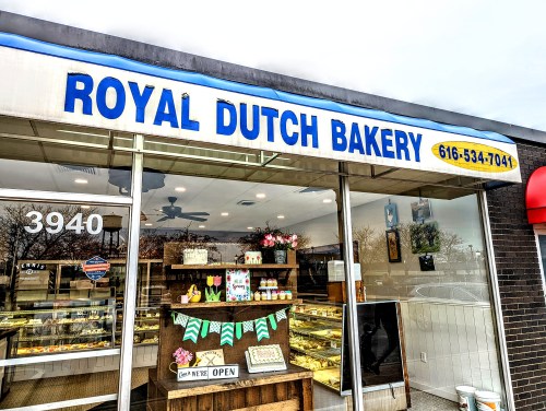 Exterior of Royal Dutch Bakery with a blue sign, open display, and decorative items in the window.