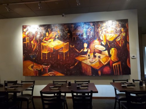 A vibrant mural depicting a lively restaurant scene with tables, chairs, and abstract figures enjoying a meal.