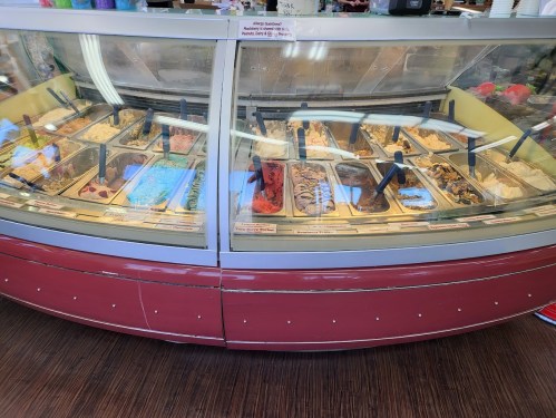A display case filled with various flavors of ice cream in a colorful ice cream shop.