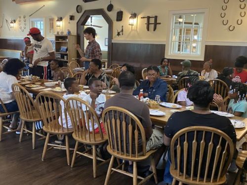 A lively gathering at a long table in a restaurant, with people enjoying food and conversation.
