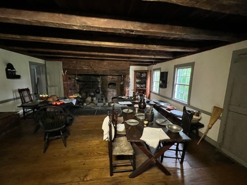 A rustic kitchen with a wooden table set for a meal, a fireplace, and traditional furnishings.