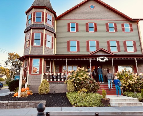 A charming multi-story building with a tower, featuring autumn decorations and people on the steps.