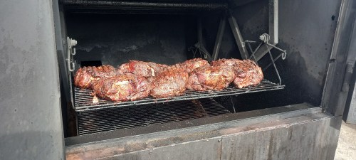 Smoked meat on a rack inside a barbecue smoker, showcasing a rich, dark crust.