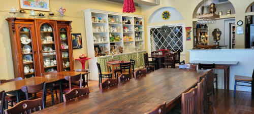 A cozy dining area with wooden tables, chairs, and display cabinets filled with collectibles and decor.