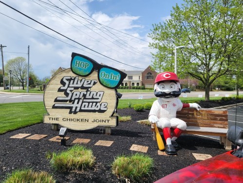 A large sign for Silver Spring House, featuring a cartoonish mascot in a baseball uniform sitting on a bench.