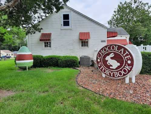 A white house with red awnings and a large sign reading "Chocolate Storybook" next to a colorful egg-shaped decoration.