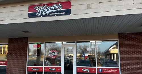 Exterior of a bakery named "Cookie's Kolaches," featuring a sign that says "Baked Fresh Daily" and an "Open" neon light.