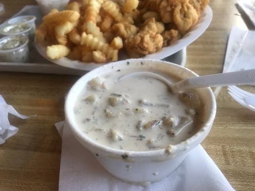 A bowl of creamy soup with chunks, served alongside a plate of crinkle-cut fries and fried chicken pieces.
