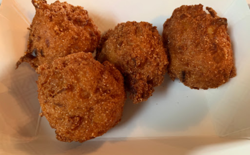 Four golden-brown, crispy fritters arranged on a white plate.