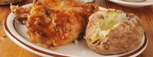 A plate featuring a juicy grilled chicken leg with barbecue sauce and a baked potato with a fluffy interior.