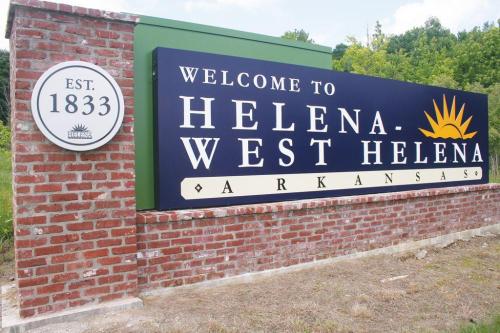 Welcome sign for Helena-West Helena, Arkansas, established in 1833, featuring a sun graphic and brick background.