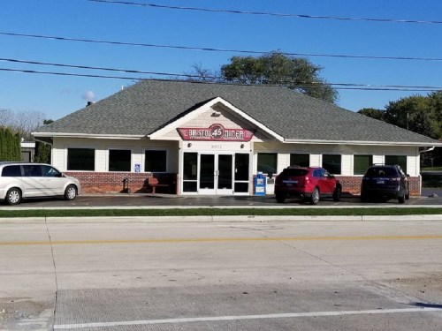 A diner with a sloped roof and large windows, featuring a sign that reads "Bristol 45 Diner," surrounded by parked cars.