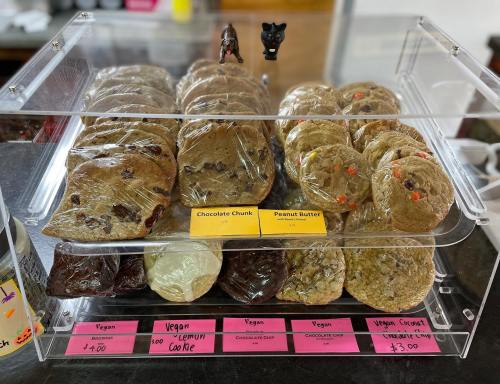 A display case filled with various cookies, including chocolate chunk and peanut butter, labeled with prices.
