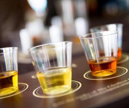 Three small plastic cups with different colored liquids on a wooden surface, blurred background.