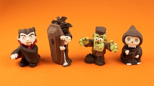 Four cartoonish Halloween figures: Dracula, a skeleton with a coffin, Frankenstein's monster, and a hooded skeleton.