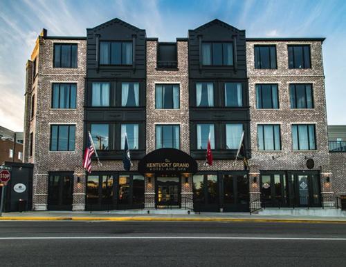 Exterior view of the Kentucky Grand Hotel, featuring a brick facade and multiple windows, with flags displayed at the entrance.