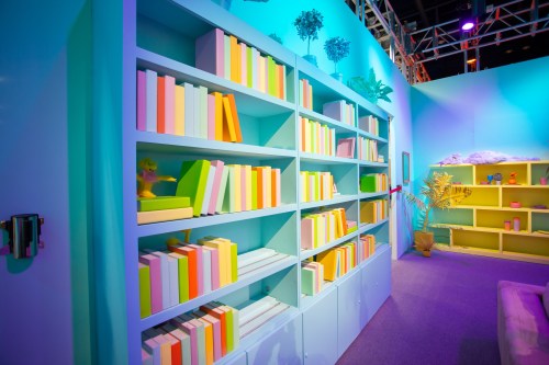 Colorful bookshelves filled with vibrant books and decorative plants in a bright, modern room.