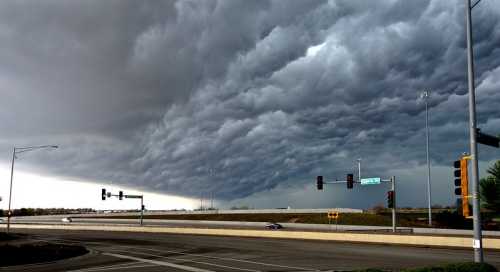 Dark, ominous storm clouds gather over a highway intersection, signaling an approaching storm.