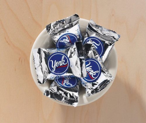 A small white bowl filled with York peppermint patties wrapped in silver foil.