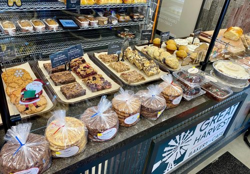 A display case filled with various baked goods, including cookies, bars, and muffins, at Great Harvest Bakery.