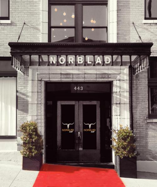 Entrance of Norblad with a red carpet, potted plants, and decorative lights above the doors.