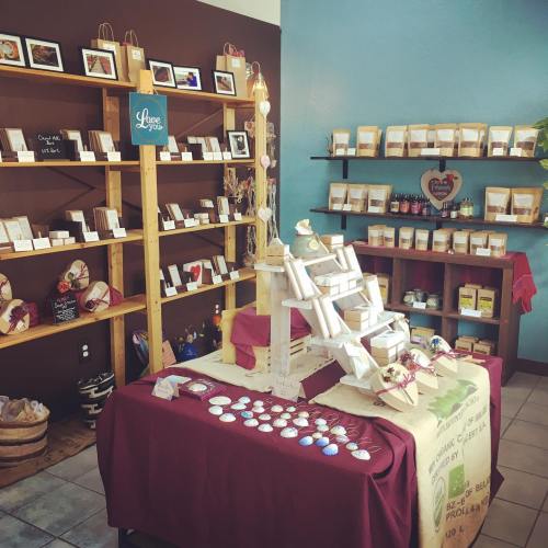 A cozy shop interior featuring wooden shelves filled with packaged goods and a display table with various items.