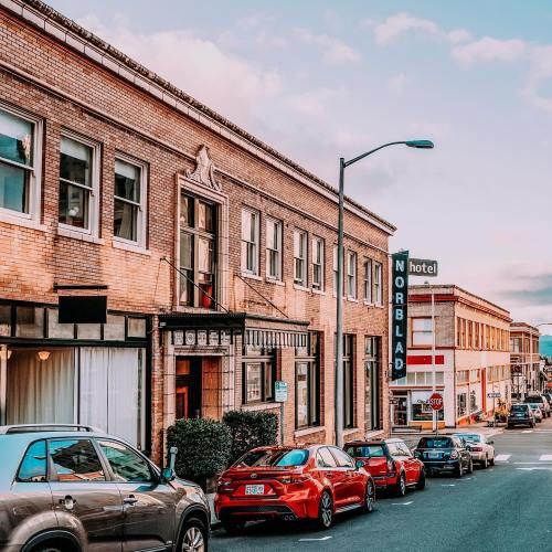 Historic buildings line a street with parked cars, featuring a hotel sign for "Norbald" in a charming urban setting.