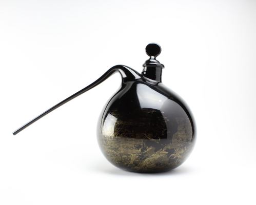 A round, black glass bottle with a long spout and a decorative top, featuring a textured gold interior.