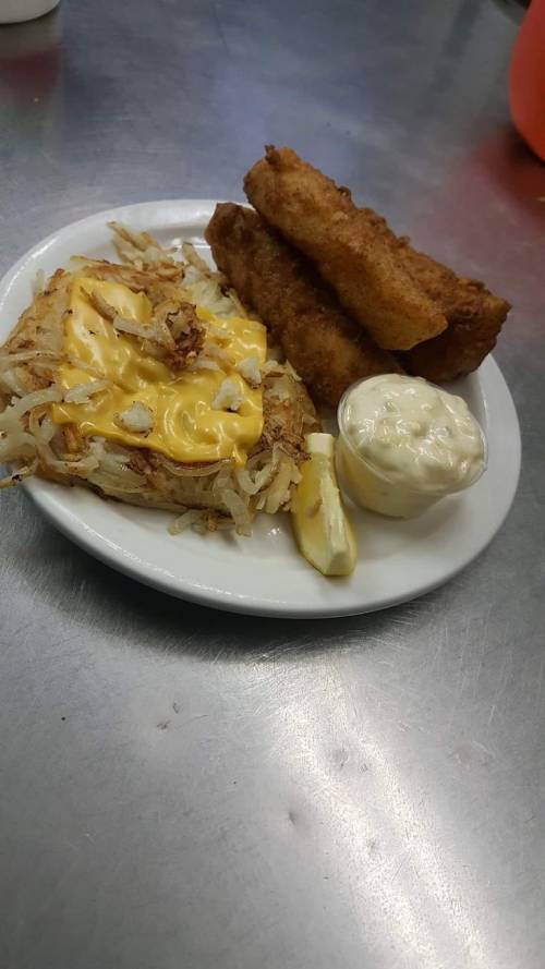A plate of crispy hash browns topped with cheese, accompanied by two fried rolls and a small cup of dipping sauce.