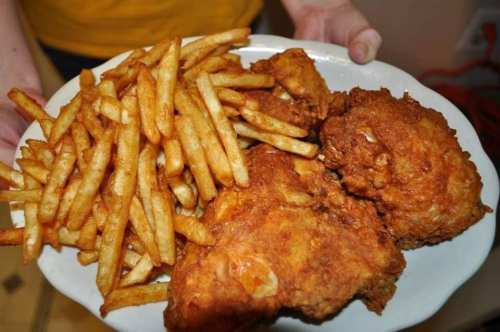 A plate of crispy fried chicken pieces served with a generous portion of golden French fries.