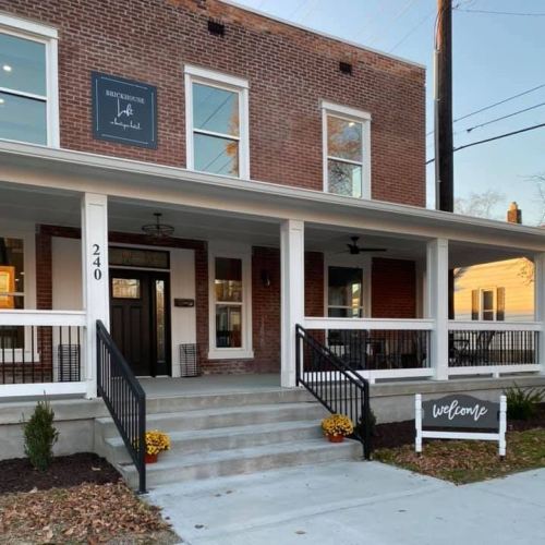 A welcoming brick building with a porch, steps, and a sign that says "welcome" in front.