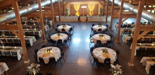 A spacious banquet hall with round tables, elegant decor, and a head table set against a wooden backdrop.