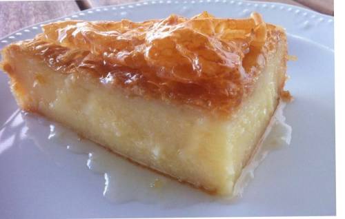 A slice of creamy dessert with a golden, crispy top, served on a white plate.
