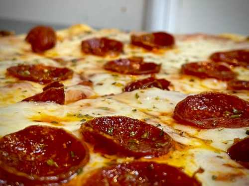 Close-up of a pepperoni pizza with melted cheese and herbs, showcasing crispy pepperoni slices on a golden crust.