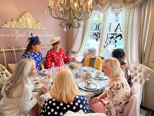 A group of women in stylish outfits enjoying tea at a beautifully decorated table in a cozy, elegant setting.