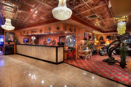 A stylish restaurant interior featuring ornate decor, chandeliers, and a vintage car display.