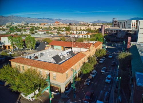 Aerial view of Hotel Congress with a cityscape and mountains in the background, showcasing urban architecture.