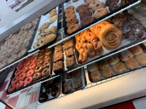 A display case filled with various donuts, pastries, and baked goods in an assortment of colors and textures.