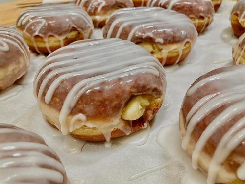 Close-up of glazed donuts with white icing drizzled on top, arranged on parchment paper.