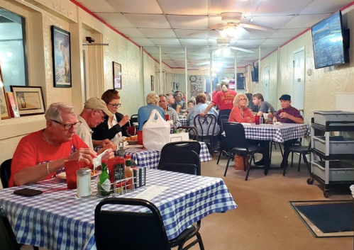 A cozy diner with patrons enjoying meals at checkered tables, featuring a warm atmosphere and casual decor.
