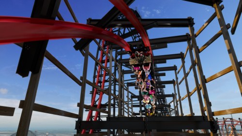 A roller coaster with riders zooming through a metal frame against a clear blue sky.