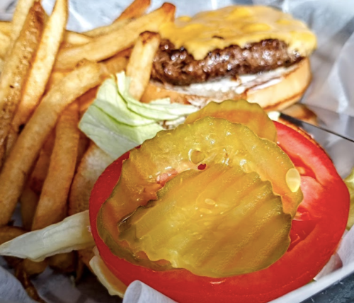 A cheeseburger with lettuce and pickles, served with a side of golden French fries.