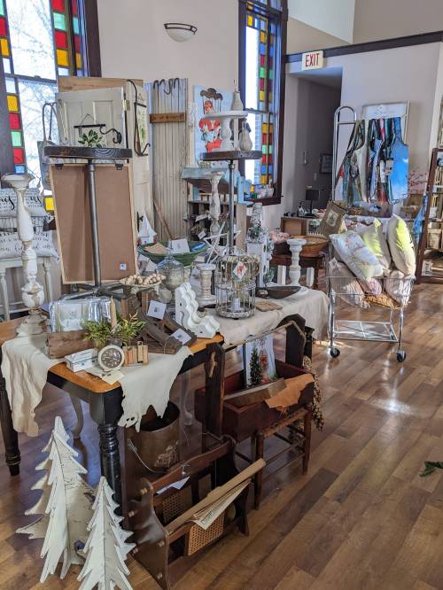 A cozy shop display featuring various decorative items, including candles, plants, and holiday decor on wooden tables.