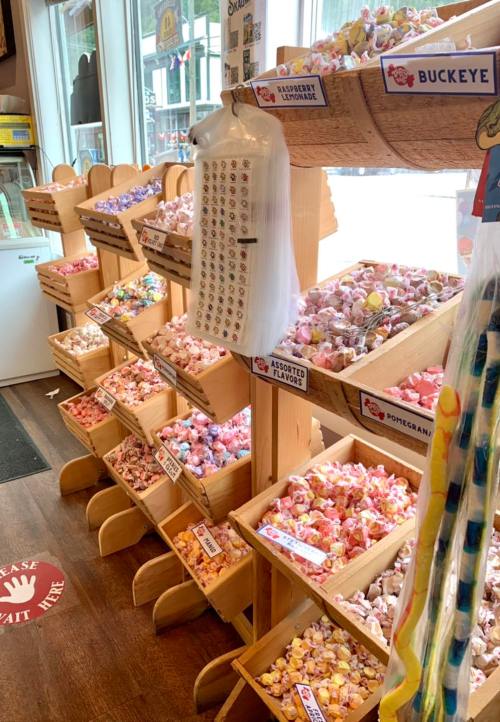 A colorful display of various candies in wooden bins, with labels for different flavors in a candy shop.