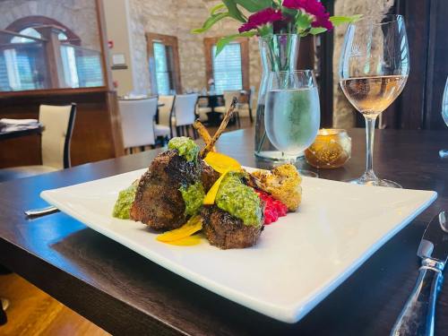 A gourmet dish featuring grilled meat with vibrant sauces, served on a white plate in an elegant restaurant setting.