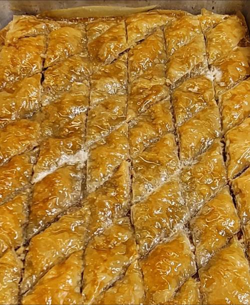 A close-up of freshly baked baklava, cut into diamond-shaped pieces, glistening with syrup.